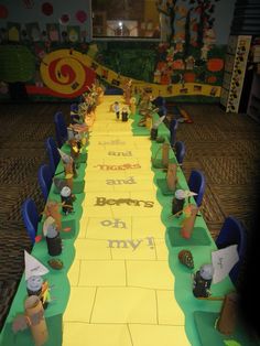 a long table is decorated with paper machs and little people on the yellow runner