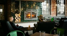 two people sitting at tables in front of a fire place