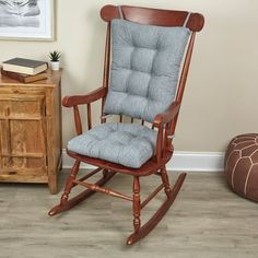 a wooden rocking chair with blue cushions in a room next to a dresser and bookcase