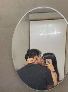 a man and woman taking a selfie in front of a mirror with their arms around each other