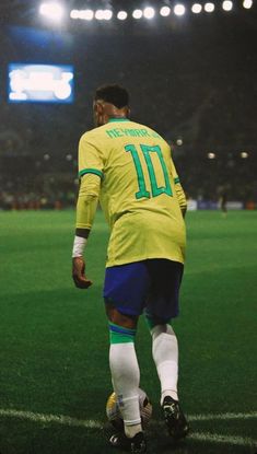 a soccer player in yellow and blue is on the field with his foot up to the ground