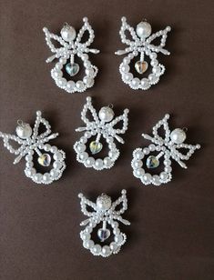 six brooches with pearls and crystals on them sitting on a brown table top