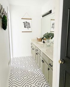 a white bathroom with black and white tile flooring next to a double sink vanity