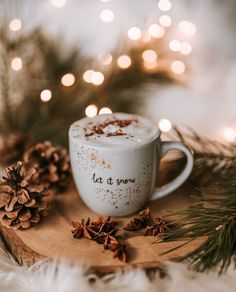 a cup of hot chocolate sitting on top of a wooden tray next to pine cones