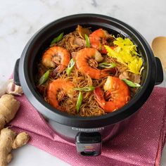 a bowl filled with noodles and shrimp on top of a pink towel