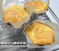 three muffins sitting in tins on top of a metal rack with wax paper