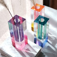 two colorful vases sitting next to each other on top of a white tablecloth