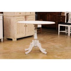 a white table sitting on top of a kitchen floor next to a cabinet and counter