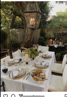 an outdoor dining table set with plates and silverware