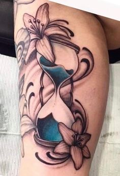 a woman's thigh with an hour and flower tattoo on it