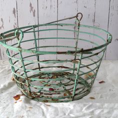 an old green metal basket sitting on top of a white sheet