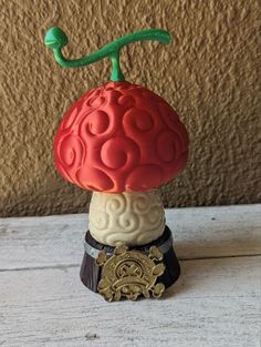 a red and white mushroom sitting on top of a wooden table next to a wall