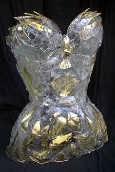 a glass sculpture with gold foil on it's bust and shoulders, in front of a black background