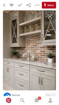 a kitchen with white cabinets and brick wall