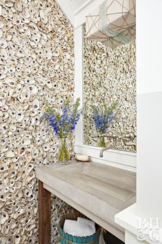 the bathroom is decorated with shells and blue flowers in vases on the sink counter