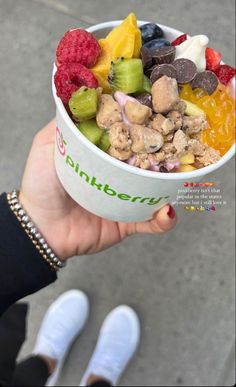 a person holding up a cup filled with fruit and nuts on top of it's side