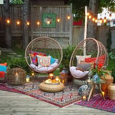 an outdoor patio with hanging lights and wicker chairs, rugs and candles on the ground