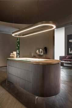 a modern kitchen with an island and round mirror on the wall, in front of a couch