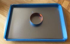 a blue tray with a ring on it sitting on top of a wooden table next to a wood floor