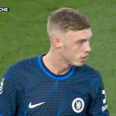 a soccer player is standing on the field with his head turned to look like he's about to kick the ball