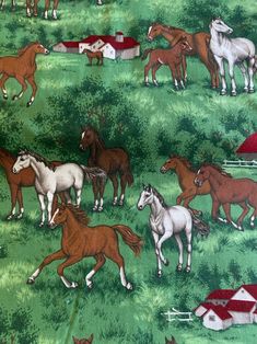 a group of horses running across a lush green field next to a red roofed barn