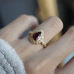 Introducing the Rose Of Garnet Diamond Ring, a captivating ring that embodies elegance and romance. At its heart lies a pear-shaped garnet, radiating deep crimson hues reminiscent of a rose in full bloom. Encircling the stone are intricate arrangement of hand-carved rose leaves, each petal etched in your choice of 14K and 18K gold, creating a delicate frame. The ring’s vintage-inspired design is adorned with sparkling diamonds that highlight the natural beauty of the garnet and the intricacy of the surrounding roses. All orders come in our Tippy Taste ring box. This ring is handmade and designed in NYC. 14K or 18K solid gold Natural pear shape garnet 11 Natural round diamonds. SI clarity. GH color, approx. 0.11ct 1.6mm ring band ** Tippy Taste Heirloom Collection is made to order. Please a Exquisite Pear-shaped Rings For Gift, Valentine's Day Pear-shaped Fine Jewelry Rings, Valentine's Day Pear-shaped Fine Rings, Luxury Pear-shaped Ruby Wedding Ring, Pear-shaped Ruby Rings With Rose Cut Diamonds, 14k Gold Pear-shaped Ruby Ring For Wedding, Teardrop Yellow Gold Ruby Ring For Wedding, Elegant Teardrop Ruby Ring For Formal Occasions, Elegant Teardrop Ring For Proposal