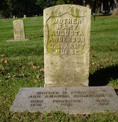 a headstone in the middle of a grassy area with two headstones on it