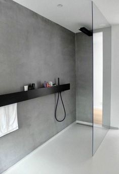 a bathroom with gray walls and black shelves on the wall, along with a white bathtub