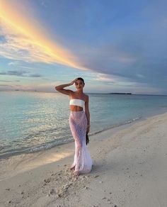 a woman in a white dress standing on the beach