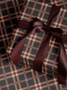 two wrapped gift boxes with brown ribbon on checkered fabric, one is empty and the other has a bow