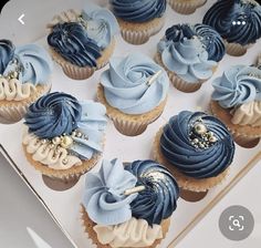 blue and white cupcakes in a box with gold decorations on the top one