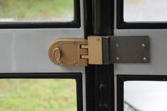 a close up of a door handle on a glass door with grass in the background