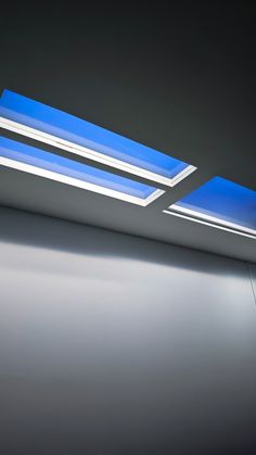 two blue and white lights on the ceiling in an empty room with no one inside