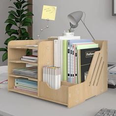 a desk with a computer keyboard and some books on it in front of a potted plant