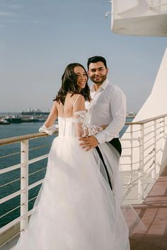 a bride and groom pose on the deck of a cruise ship