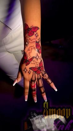 a woman's hand with tattoos on it and butterflies painted on the palm,