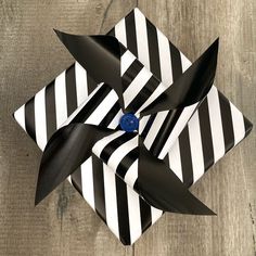 a black and white striped bow with a blue button in the center on a wooden surface