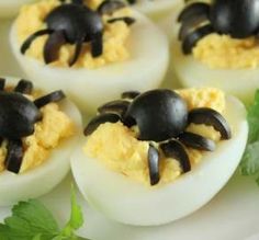 devil's eggs stuffed with cheese and black olives on a white platter