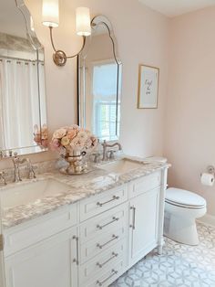 a bathroom with pink walls and white cabinets