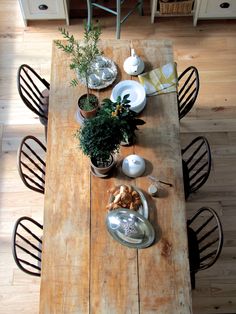 an overhead view of a wooden table with chairs and dishes on it, in the middle of a wood floored dining room