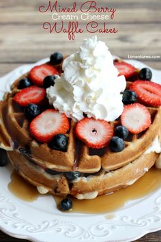 a stack of waffles topped with whipped cream and strawberries on a white plate