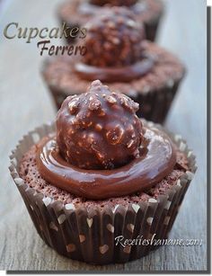 three cupcakes with chocolate frosting and sprinkles on top sitting on a wooden table