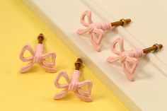 three little pink bows are on the handles of some door knobs in front of a yellow and white background