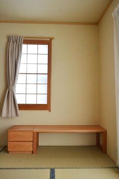 an empty room with a bench and window in the corner, next to a rug on the floor