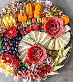 a platter filled with cheese, fruit and meats on top of a table