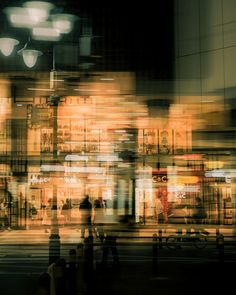 blurry photograph of people walking in front of a building at night with street lights