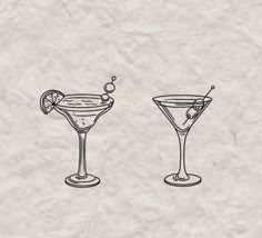 two martini glasses with olives and an orange slice