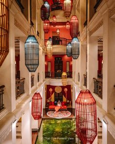 the interior of a hotel lobby with red and blue lanterns hanging from the ceiling