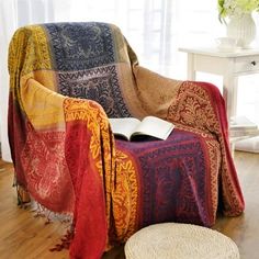 a chair with a blanket on top of it next to a book and a basket