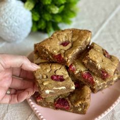 a pink plate topped with brownies and raspberry squares on top of a table